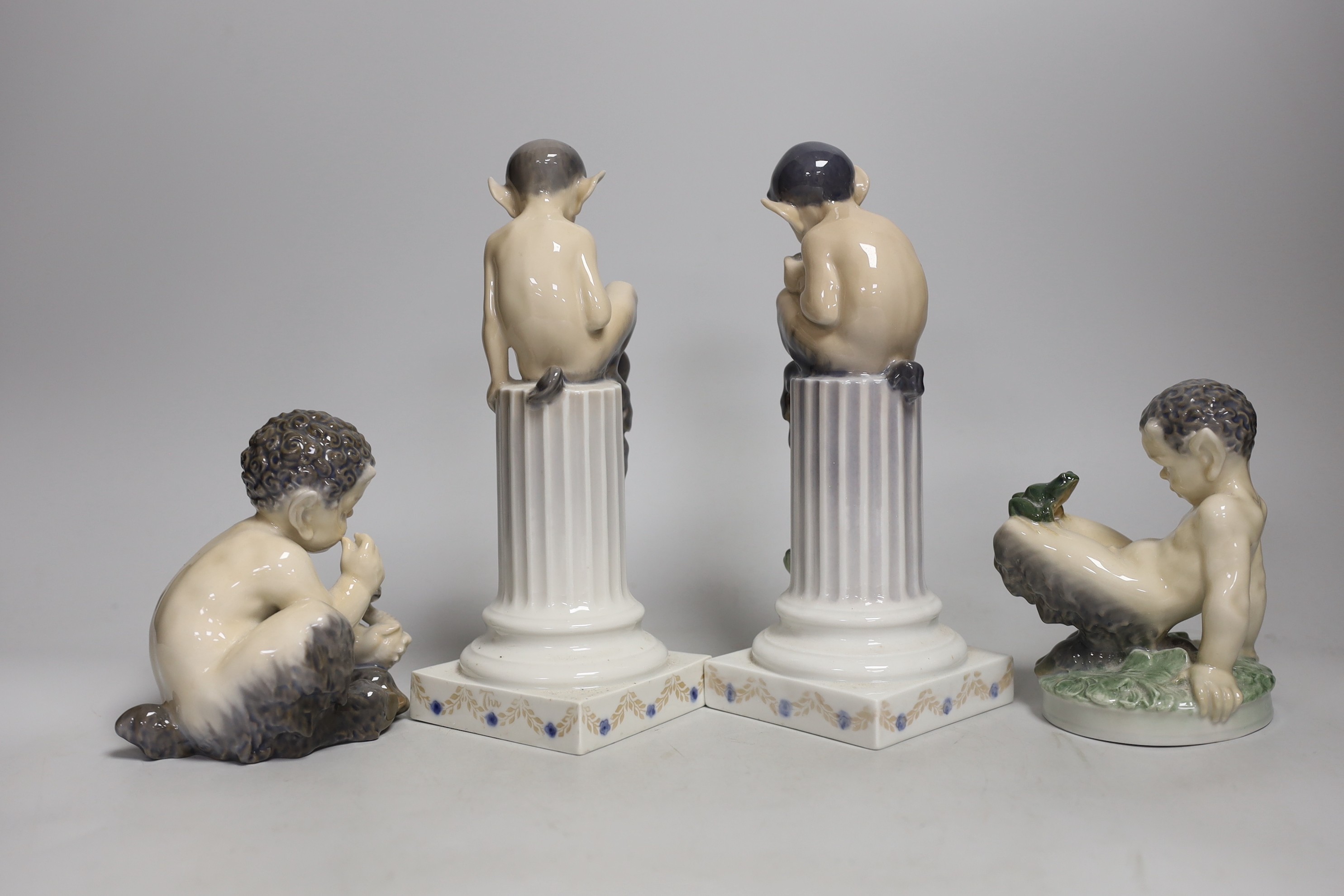 Four Royal Copenhagen models of Fauns, two playing musical instruments, one with a snake, the other with a frog. Tallest 21cm